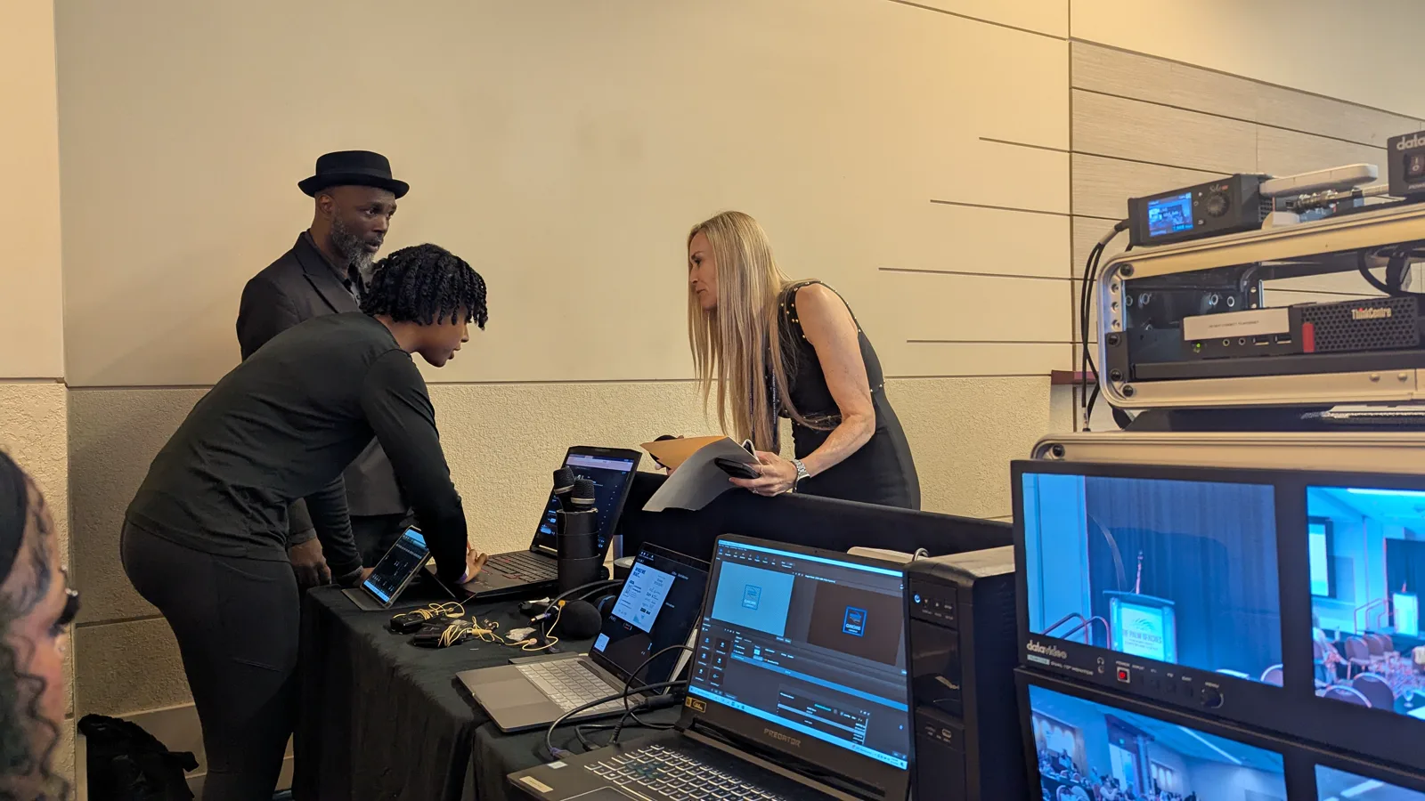 Production team preparing laptops and broadcast equipment at the conference control position