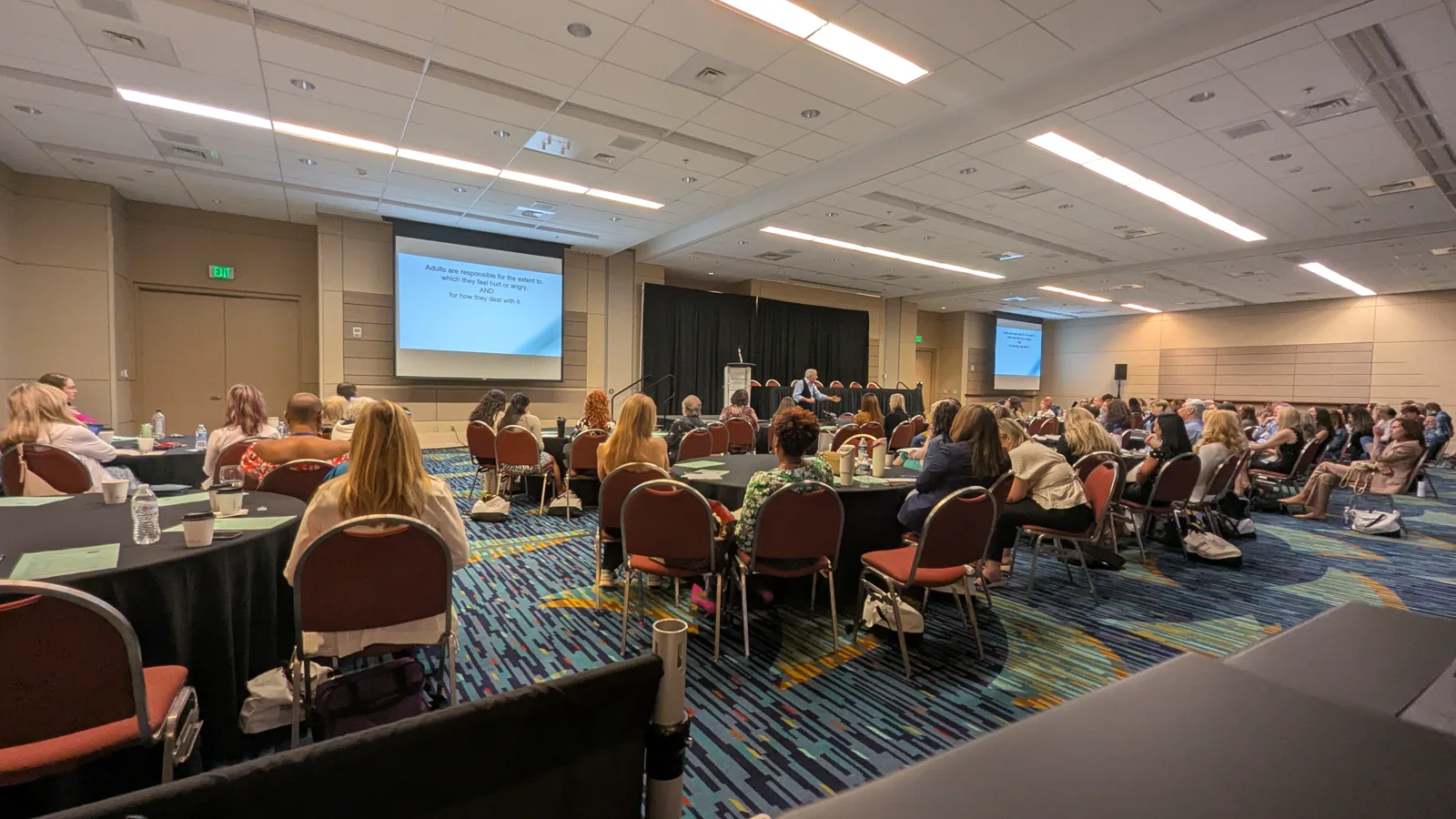 Conference audience watching a speaker at the stage with two presentation screens