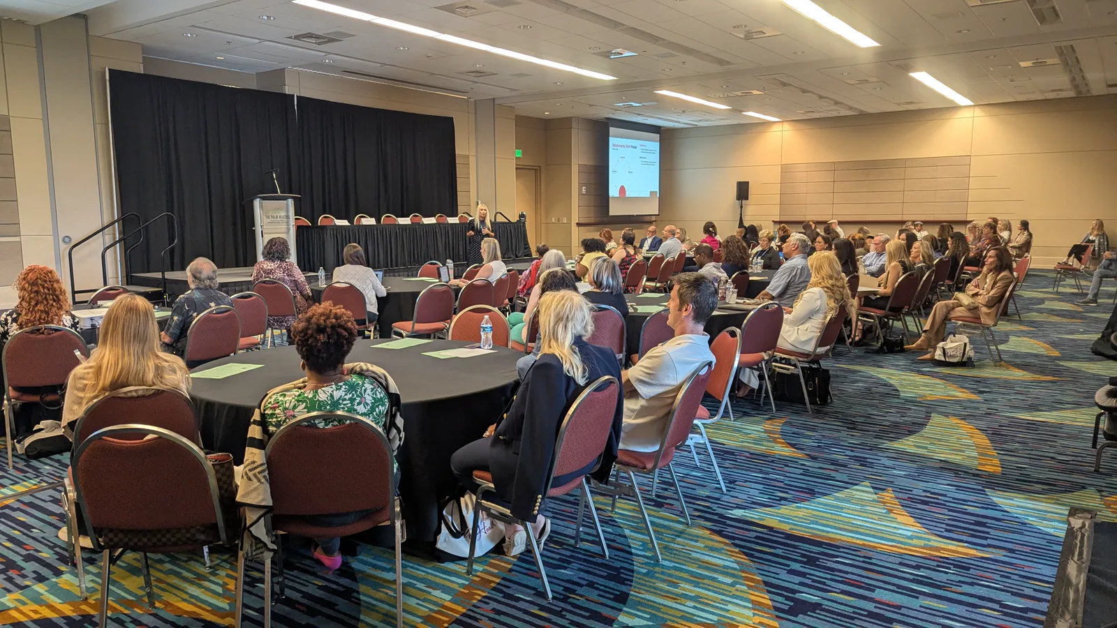 Wide view of the Still Wanting conference audience and stage in West Palm Beach