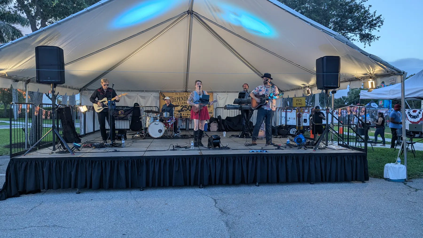 The Experience band performing on stage at twilight during the Village of Palm Springs 4th of July celebration, with full Primestar crewing and distributed audio deployment