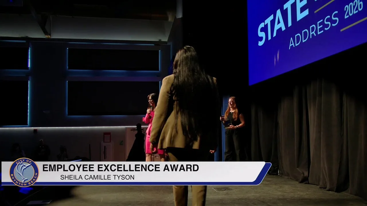 An Employee Excellence Award presented on stage beneath the State of the City Address 2026 screen in Boynton Beach