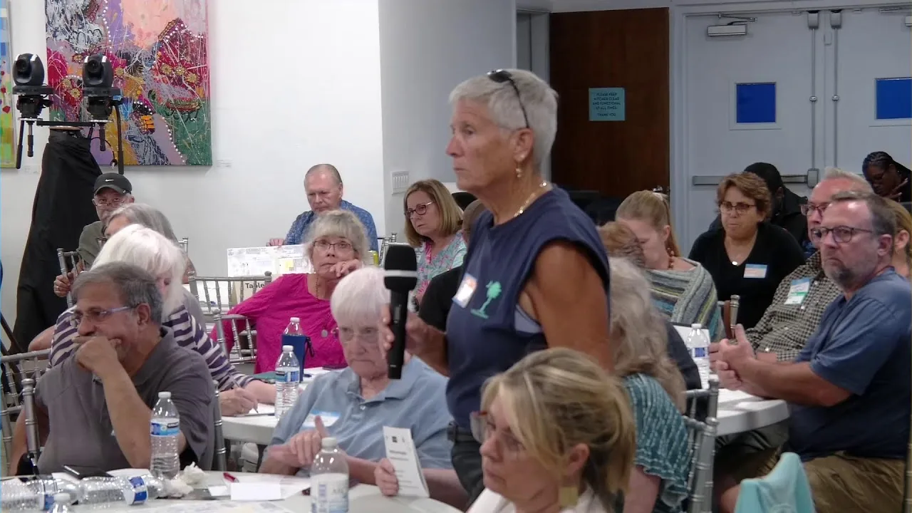A resident speaks into a handheld microphone during the community charrette at the Wiener Museum of Decorative Arts