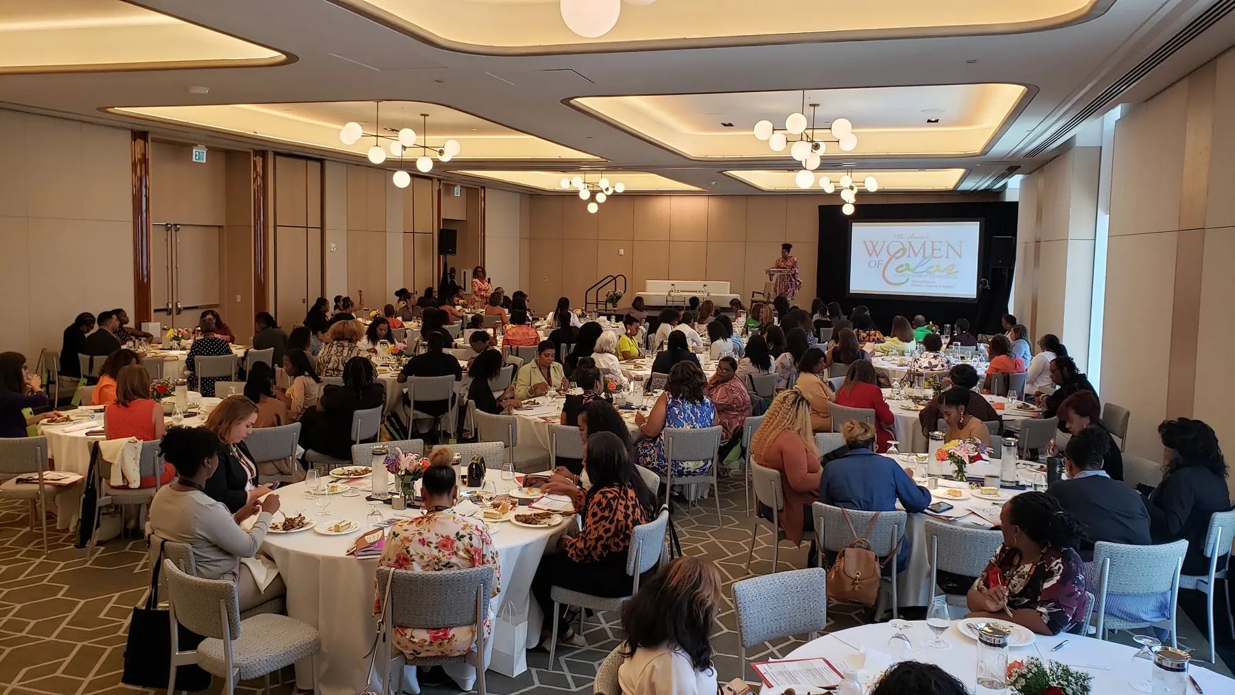 Full ballroom at the Women of Color Empowerment Conference in Fort Lauderdale with the branded presentation screen