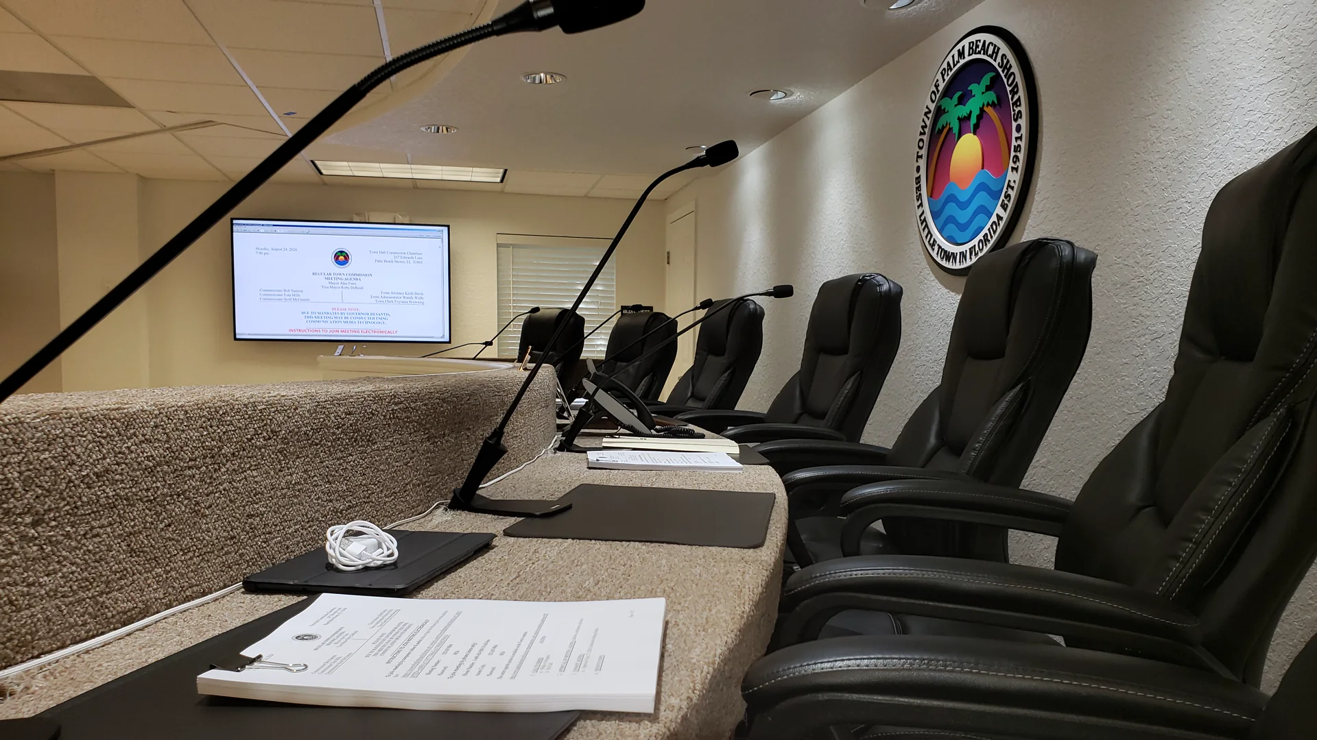 Palm Beach Shores municipal chamber with council microphones, agenda display, and presentation positions