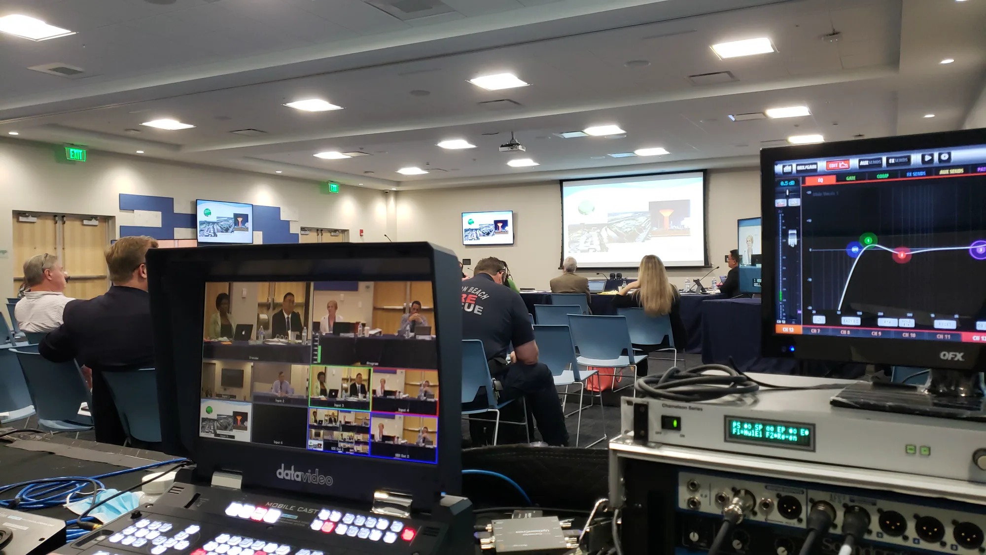 Municipal meeting room viewed from a production position, with multiview monitors and switching equipment in the foreground